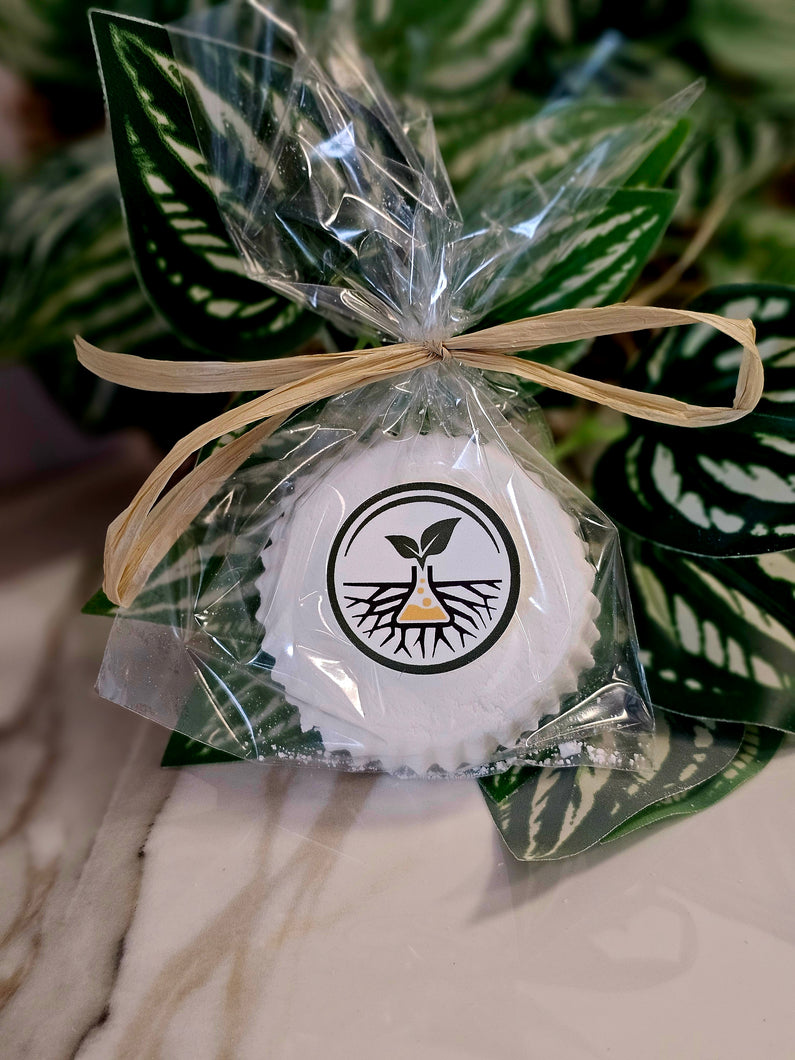 White product in clear packaging with a bow, against a green leafy background